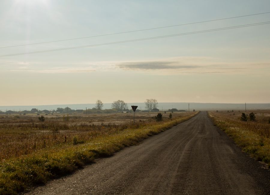 Empty dirt road stretching through open farmland toward the horizon